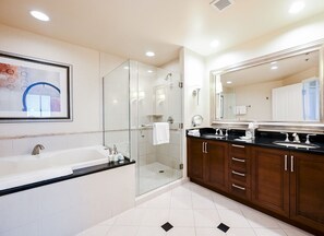 Un baño moderno con ducha de mampara de vidrio, un espejo grande y una bañera.