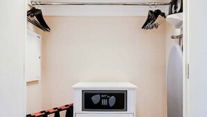 Pieni makuuhuone, jossa on kerrossänky, pieni valkoinen lipasto ja vaatekaappi, jossa on henkarit.