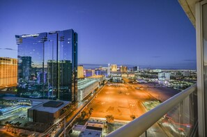 A high-rise hotel with a modern glass facade, a parking area, and a view of the cityscape at dusk. - SVS: Sphere Strip View Balcony | Signature at MGM (Las Vegas)