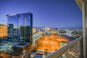 Ein Hochhaus-Hotel mit moderner Glasfassade, einem Parkplatz und Blick auf die Stadt bei Abenddämmerung.