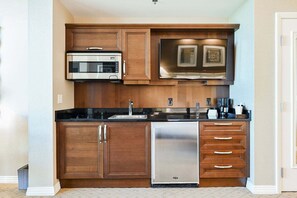 A compact kitchen with a microwave, dishwasher, and wooden cabinets. - SVS: Sphere Strip View Studio | Signature at MGM (Las Vegas)