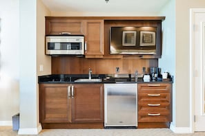 A compact kitchen with a microwave, dishwasher, and wooden cabinets. - Studio • No Resort Fee • Free Parking A31B3 (Las Vegas)
