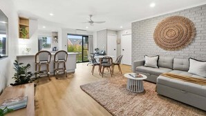 Una sala de estar moderna con un sofá gris, una mesa de centro redonda y un comedor con sillas y una mesa.