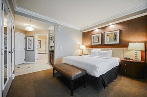 Ein Hotelzimmer mit Bett, Nachttischen, einer Bank, einem Kleiderschrank und einem durch eine offene Tür einsehbaren Badezimmer.