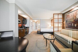 A hotel room with a dining table, a sofa, a bed, a TV, and a painting on the wall. - Studio • No Resort Fee • Free Parking A3B3 (Las Vegas)