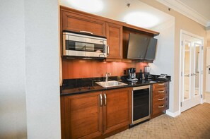 A compact kitchen with wooden cabinets, a built-in microwave, a coffee maker, and a dishwasher. - Studio • No Resort Fee • Free Parking A3B3 (Las Vegas)