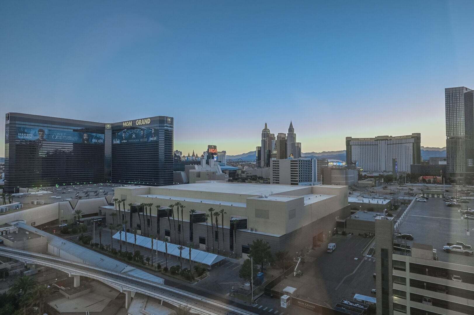 Un paisaje urbano con edificios destacados, entre ellos el hotel MGM Grand, un amplio estacionamiento y una autopista.