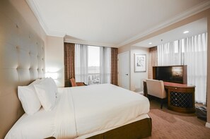 A hotel room with a large bed, a desk with a TV, and a view of the city. - SVS: One Bedroom | Balcony | Signature at MGM (Las Vegas)