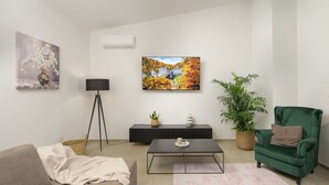Ett vardagsrum med en soffa, ett soffbord, en tv och dekorativa föremål.