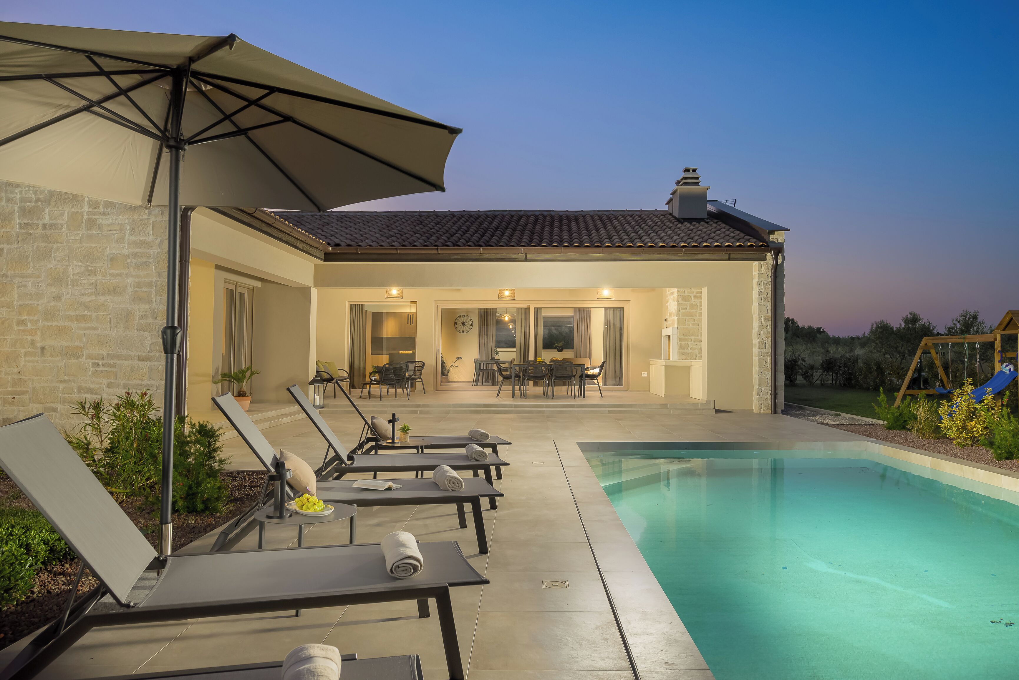 Un espace aménagé au bord de la piscine, avec des chaises longues, une table et un ensemble de mobilier de jardin.