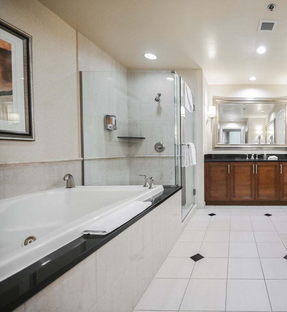 A modern bathroom with a large bathtub, a shower, and a vanity with a mirror.