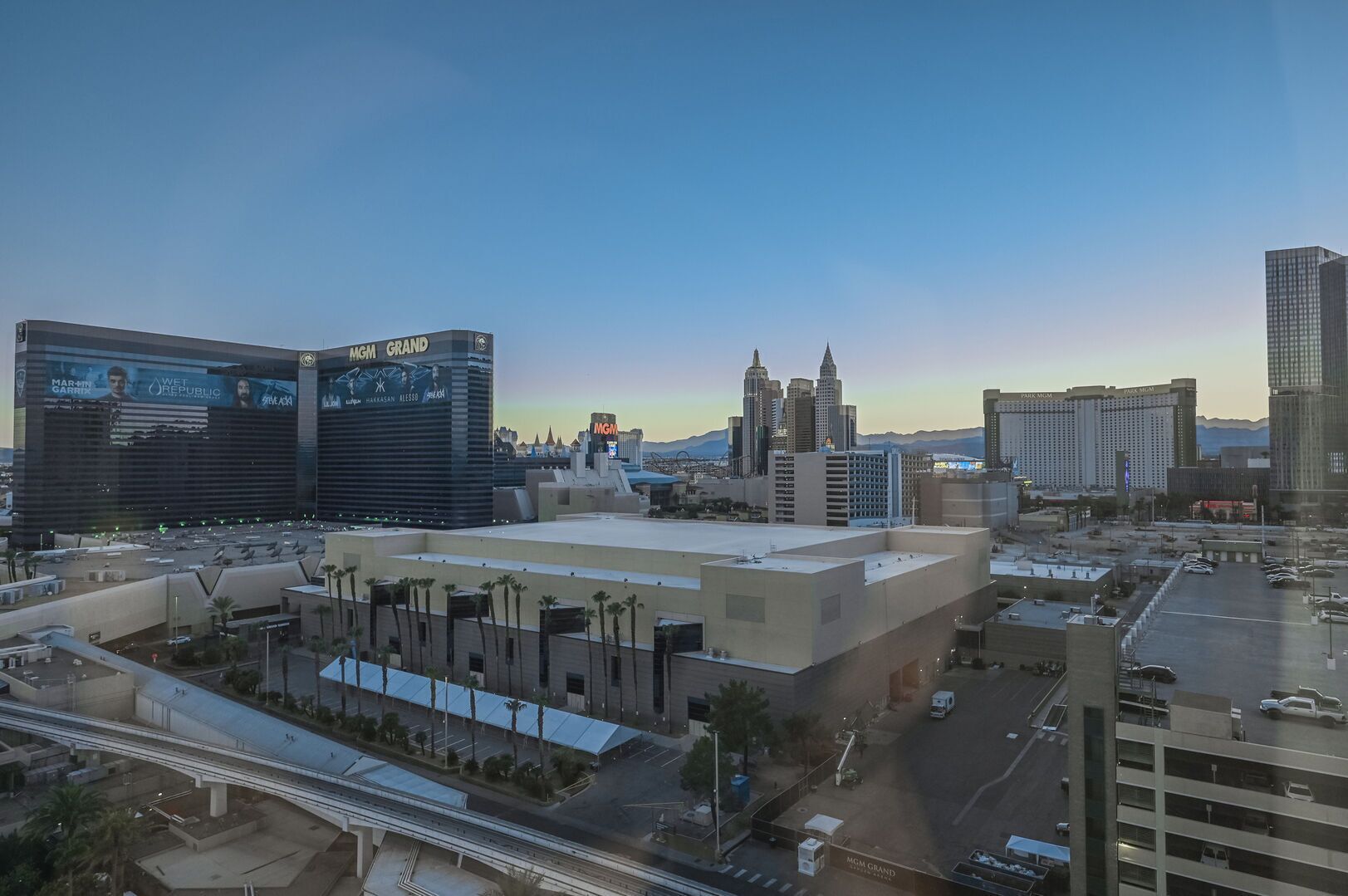 A cityscape with prominent buildings including the MGM Grand and a large hotel with a flat roof and parking lot.