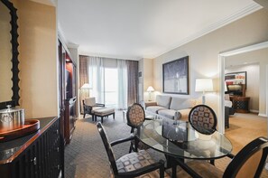 Ein Hotelzimmer mit einem Glastisch, zwei Sofas, einem Fernseher und Blick ins Freie.