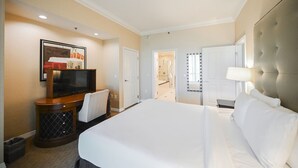 Una camera d'albergo con un letto grande, una televisione, una scrivania e uno specchio.