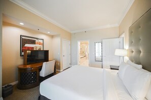 A hotel room with a large bed, a TV, a desk, and a mirror.