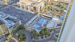 Un hotel con un ampio parcheggio, diverse piscine e un cortile centrale con palme.