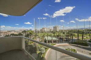 Ein Balkon mit Blick auf eine Stadtlandschaft, einschließlich Gebäude und Palmen.