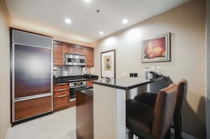 Een compacte keuken met moderne apparatuur, een klein eetgedeelte en een enkele stoel.