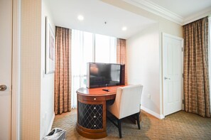 Une chambre d’hôtel équipée d’une télévision, d’un bureau, d’une chaise, d’une armoire et d’une porte.