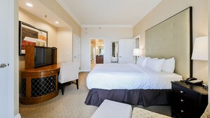 Camera d'albergo con un letto grande, una scrivania con televisore, un comò e uno specchio.