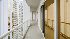 Un corridoio con balconi, una porta vetrata e vista su un edificio a più piani.
