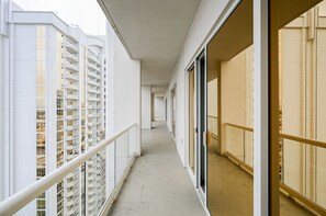 Ein Korridor mit Balkonen, einer Glastür und Blick auf ein mehrgeschossiges Gebäude.