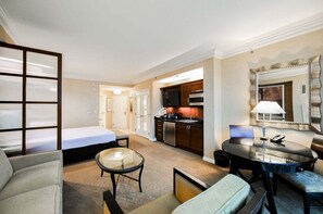 A hotel room with a bed, a seating area with a table and chairs, a kitchenette, and a bathroom. - SVS: Strip View Studio | Signature at MGM (Las Vegas)