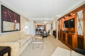 A living room with a sofa, coffee table, TV, and a dining area with chairs and a table. - Strip View One Bedroom | Balcony| Signature at MGM F8Q2 (Las Vegas)