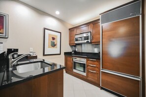 A kitchen with a stainless steel sink, a microwave, an oven, and wooden cabinets. - Strip View One Bedroom | Balcony| Signature at MGM F8Q2 (Las Vegas)