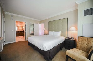 Une chambre d’hôtel avec un grand lit, une table de chevet avec une lampe, une chaise et un miroir au mur.