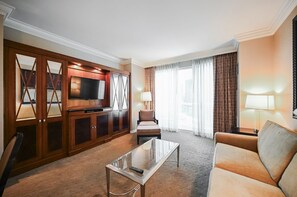A hotel room with a sofa, a TV, a glass coffee table, and a seating area with a lamp. - SVS: One Bedroom | Strip View Balcony | MGM Signature (Las Vegas)