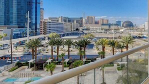 A cityscape with modern buildings, palm trees, and a clear sky. - SVS: One Bedroom | Strip View Balcony | MGM Signature (Las Vegas)