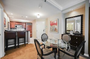A modern kitchen with a microwave, oven, and a dining area with a glass table and chairs. - SVS: One Bedroom | Sphere Strip View Balcony | MGM Signature (Las Vegas)