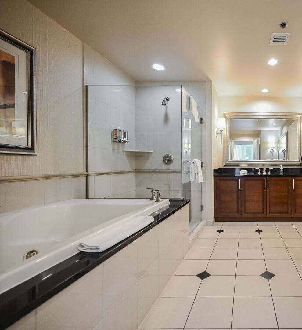 A modern bathroom with a large bathtub, a glass-enclosed shower, and a vanity with a mirror.