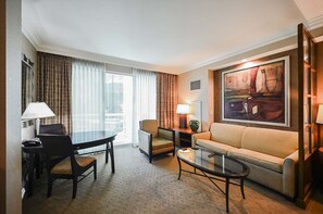 Ein Hotelzimmer mit Esstisch, einer Couch, einem Couchtisch und einem Bild an der Wand.