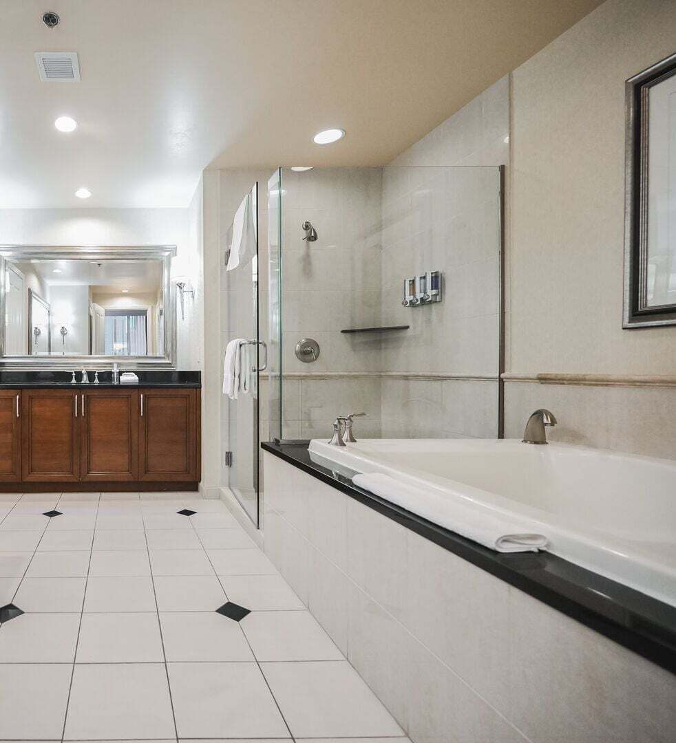 Une salle de bain moderne avec une grande baignoire, une douche à l’italienne et un meuble-lavabo avec un miroir.