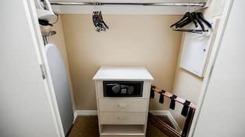 Un petit placard étroit, avec un meuble de rangement blanc, une tringle à vêtements et un porte-serviettes.