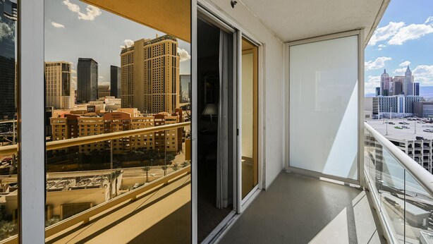 A balcony with a cityscape view, including high-rise buildings and a parking area. - SVS: Strip View Balcony | Signature at MGM (Las Vegas)