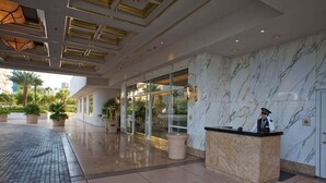 A hotel lobby with a reception desk, marble walls, and a glass entrance. - SVS: PH Floor Studio | Signature at MGM (Las Vegas)