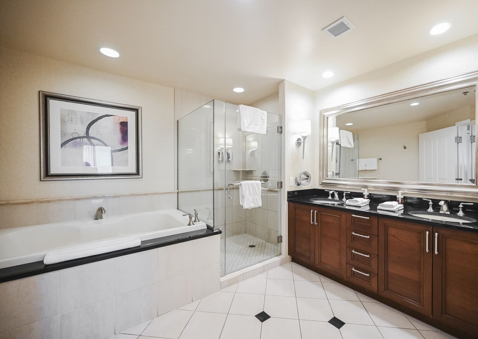 A modern bathroom with a bathtub, a glass-enclosed shower, and a large mirror.