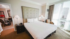 A hotel room with a large bed, two bedside tables, a chair, and a view of the city through the window. - SVS: One Bedroom | Strip View Balcony | MGM Signature (Las Vegas)