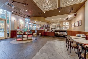 Eine Bäckerei mit einer zentralen Theke, einer Sitzgelegenheit und Vitrinen.