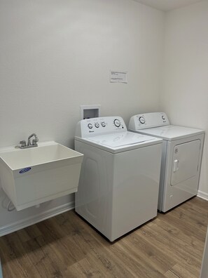 A laundry room with a sink, two washing machines, and a dryer. - Beautiful home in The Villages for those active individuals of 55+ years. (The Villages)