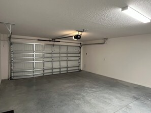 Un garage doté d’une porte métallique fermée, d’un sol en béton et d’un luminaire fluorescent au plafond.