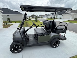 A golf cart parked on a residential driveway. - Beautiful home in The Villages for those active individuals of 55+ years. (The Villages)