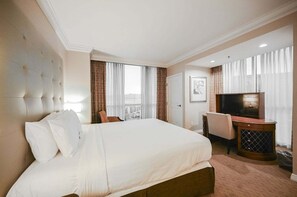 Une chambre d’hôtel avec un grand lit, une télévision, un bureau et une chaise.