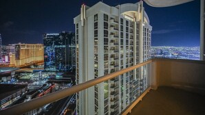 Un hôtel de grande hauteur doté de nombreux balcons, offrant une vue sur le paysage urbain, et un bâtiment imposant aux fenêtres illuminées en arrière-plan.