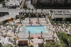 A rooftop pool area with multiple lounge chairs, palm trees, and a swimming pool. - SPHERE Strip View One Bedroom | Balcony| Signature at MGM F38Q3 (Las Vegas)