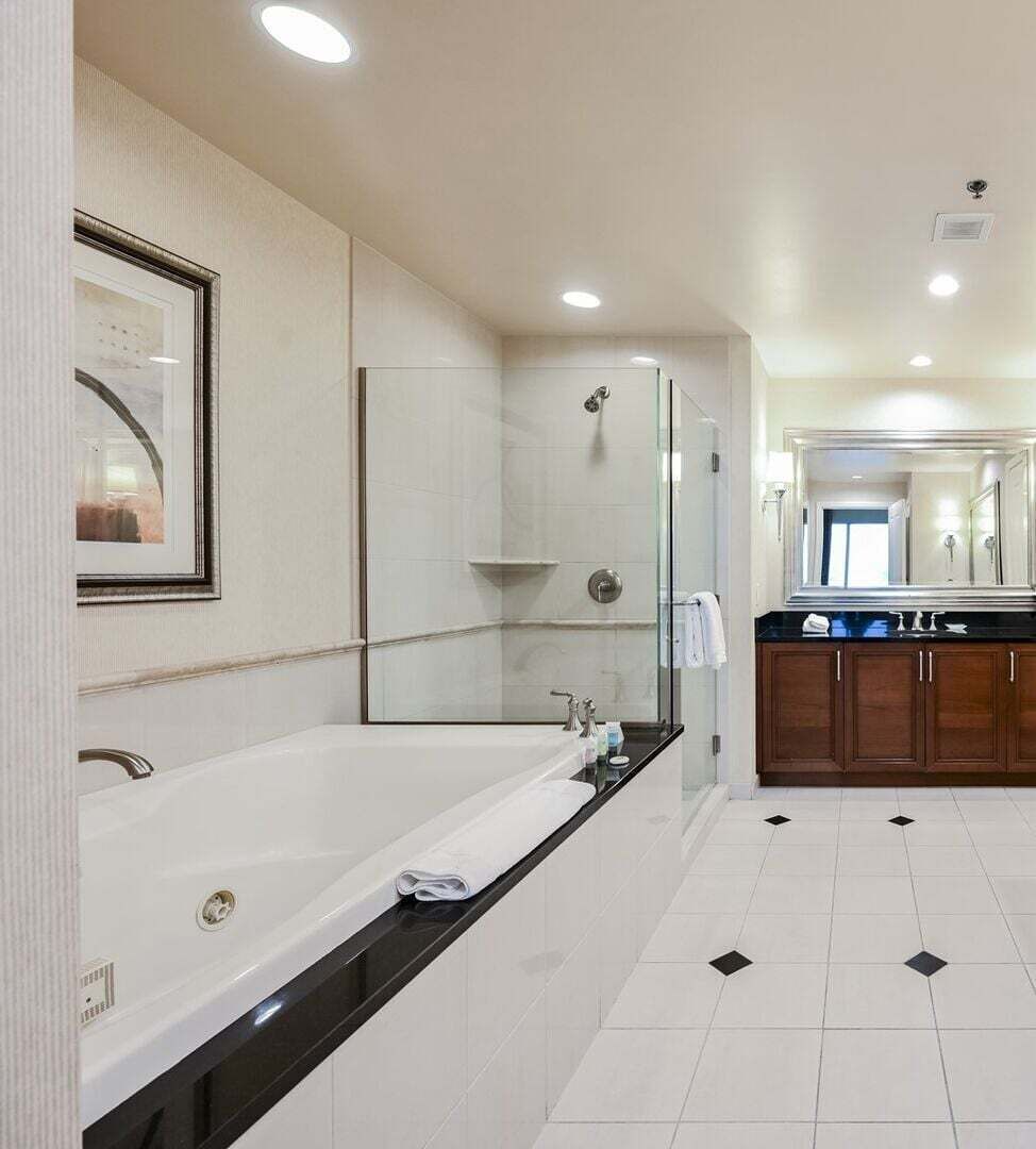 Une salle de bain moderne dotée d’une grande baignoire, d’une cabine de douche en verre et d’un espace lavabo séparé.