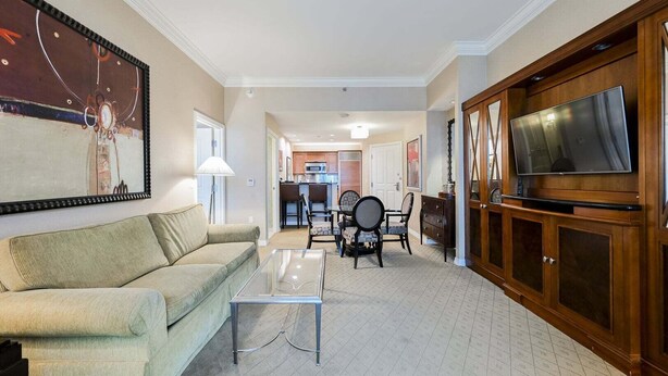A living room with a sofa, coffee table, TV, and dining area with chairs and a table. - SPHERE Strip View One Bedroom | Balcony| Signature at MGM F38Q3 (Las Vegas)